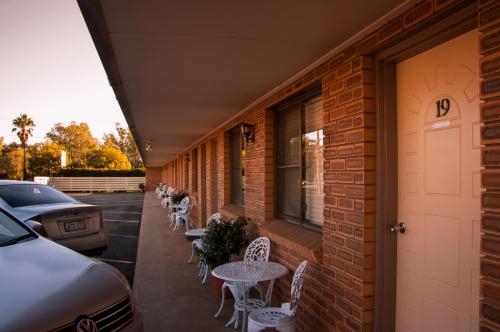 eine Terrasse mit Tischen und Stühlen in einem Backsteingebäude in der Unterkunft Mid Town Inn Narrabri in Narrabri