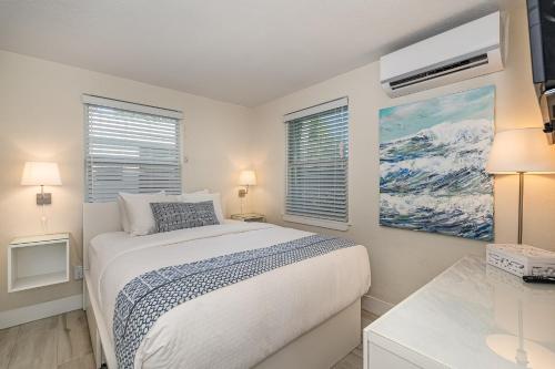 a white bedroom with a bed and two windows at Wonder Place Wprivate Patio Next To The Beach in Cocoa Beach