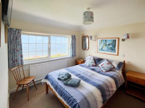 a bedroom with a bed with a teddy bear on it at Coastguard Cottage in Downderry