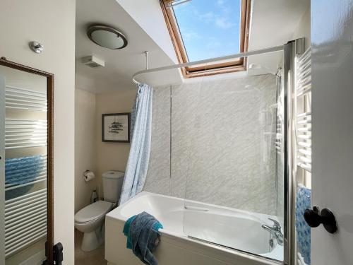 a bathroom with a shower and a tub and a toilet at Coastguard Cottage in Downderry