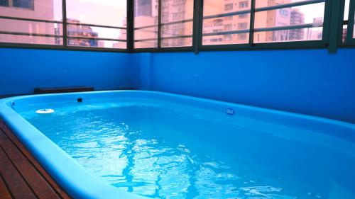 Hotel Athos في بوينس آيرس: حوض استحمام أزرق في غرفة مع نافذة