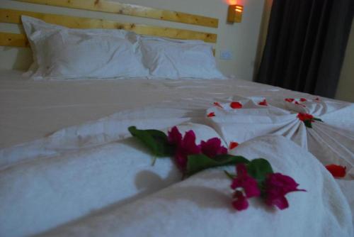 a white bed with white sheets and flowers on it at PrivHotel - Himandhoo in Himandhoo 