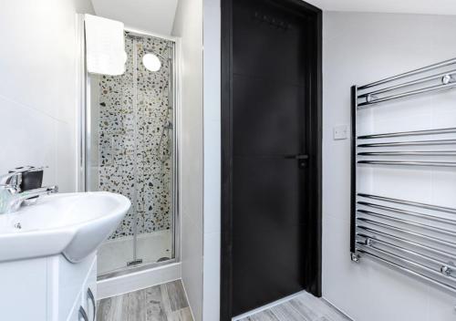 a bathroom with a shower and a white sink at Bright & Colourful House - Best for a Large Groups in London