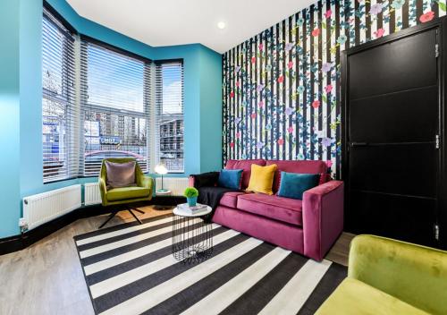 a living room with a purple couch and two chairs at Bright & Colourful House - Best for a Large Groups in London