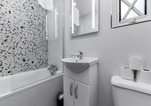 a white bathroom with a sink and a shower at Bright & Colourful House - Best for a Large Groups in London
