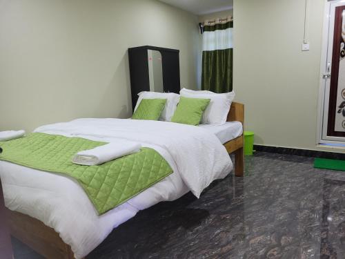 a bedroom with a large bed with green sheets and pillows at Vati guesthouse in Shillong