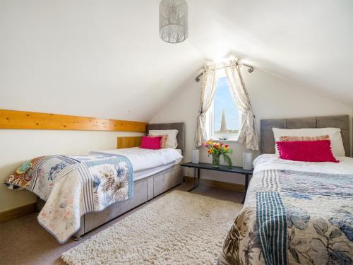 a bedroom with two beds and a window at Pentire in Holbeton