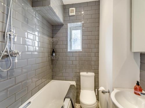 a bathroom with a tub and a toilet and a sink at Wharfedale Cottage in Harrogate