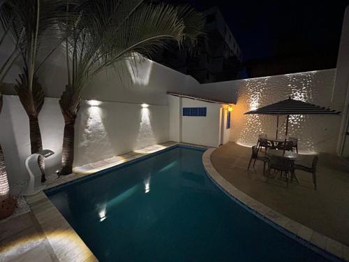 a swimming pool at night with a table and chairs at Kyros Pousada in Maceió