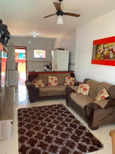 a living room with two couches and a ceiling fan at Casa com piscina- condomínio verão vermelho II UNAMAR CABO FRIO in Cabo Frio