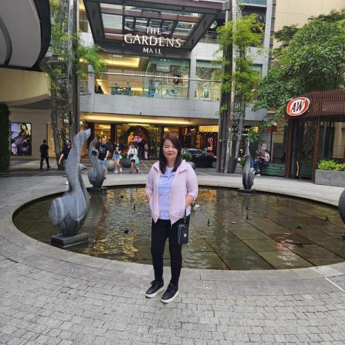 Eine Frau, die vor einem Brunnen in einer Stadt steht. in der Unterkunft Bayview hotel，pinang in Kuala Lumpur