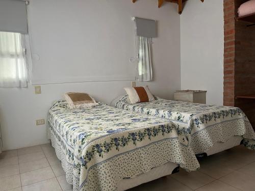 2 Betten in einem Zimmer mit weißen Wänden in der Unterkunft La calma in Puerto Madryn
