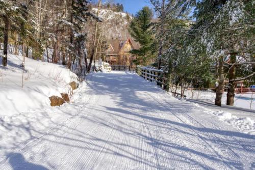 a snow covered road in front of a house at Le Plateau East by Tremblant Vacations in Mont-Tremblant