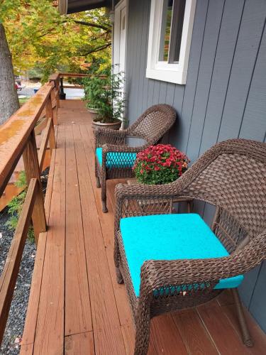 a porch with wicker chairs and a table and flowers at Chic and Stylish home Hot tub,4 bedrooms, game movie room, firepit, arcades, playground on site 2 min walk from pool and lake in Tobyhanna