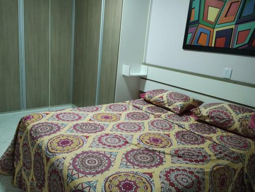 a bed with a quilt and two pillows on it at APARTAMENTO SOLAR DA PRAÇA, Aconchegante e Climatizado in Torres