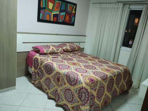 a bedroom with a bed with a colorful bedspread at APARTAMENTO SOLAR DA PRAÇA, Aconchegante e Climatizado in Torres