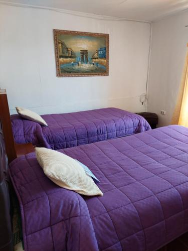 two beds in a room with purple sheets at Noface in Los Vilos