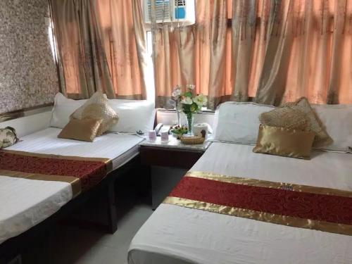 twee bedden in een kamer met oranje gordijnen bij United Co-Operate Guest House (7/F) in Hong Kong
