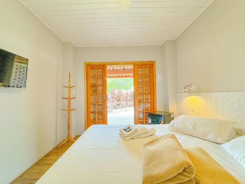 Pousada Ar da Montanha في سيرا نيجرا: غرفة نوم بسرير ابيض عليها مناشف