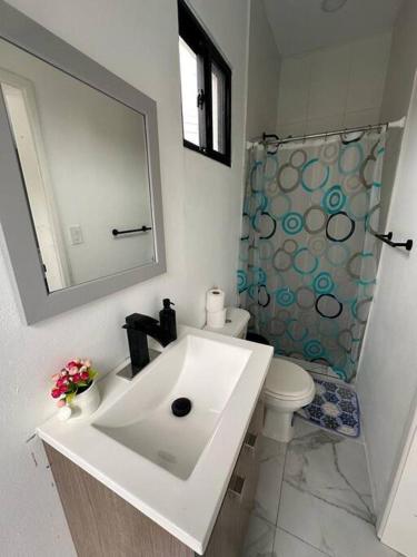 a bathroom with a sink and a toilet and a mirror at Villa Casa Blanca. in Puerto Cortés