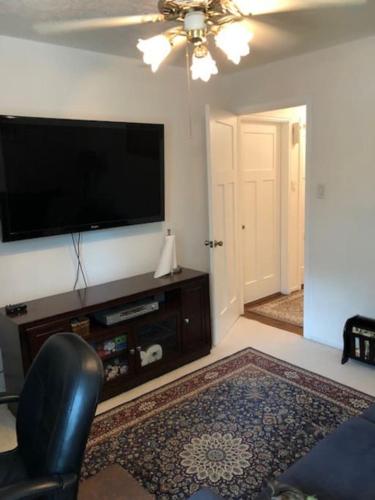 a living room with a flat screen tv and a chair at 2 room luxury suite near airport & The Woodlands in Houston