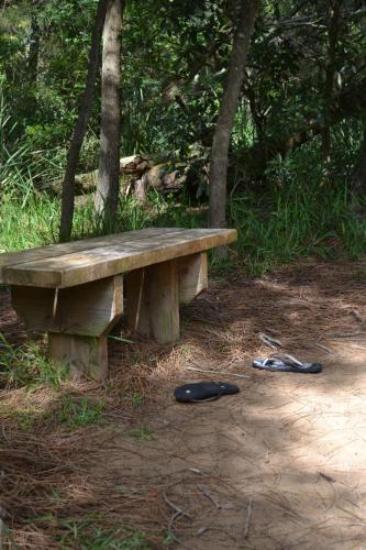 a wooden bench with a pair of shoes next to it at Manyana Beach Tiny Stays in Manyana
