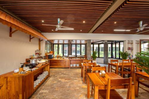 a restaurant with wooden tables and chairs and windows at Bauhinia Resort & Spa Phu Quoc in Phu Quoc