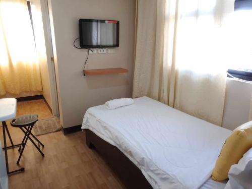 ein kleines Schlafzimmer mit einem Bett und einem TV an der Wand in der Unterkunft SEAVIEW INN in Catbalogan