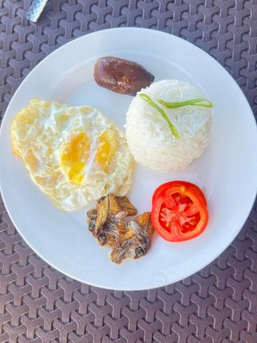 a plate of food with eggs and rice and a tomato at Villa Mariano Travellers Pad in Laoag