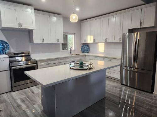 uma cozinha com armários brancos e um frigorífico de aço inoxidável em Turquoise Escapes em Black Point