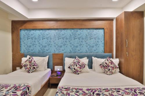 two beds in a room with a blue wall at HOTEL REST INN in Gandhinagar