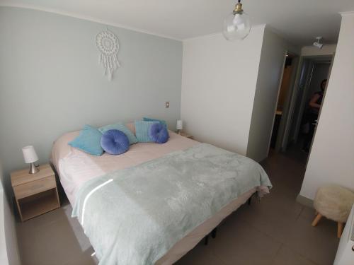 Un dormitorio con una cama con almohadas azules. en Departamento Laguna del Mar, en La Serena