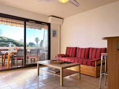 - un salon avec un canapé rouge et une table dans l'établissement Appartement Le Lavandou, 1 pièce, 4 personnes - FR-1-251-202, au Lavandou