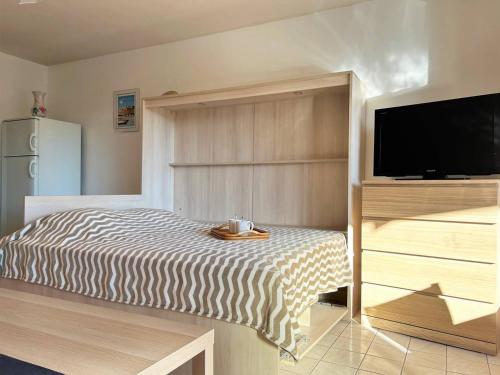 une chambre avec un lit et une télévision à écran plat dans l'établissement Studio Climatisé avec Terrasse et Parking au Centre du Lavandou - FR-1-251-202, au Lavandou