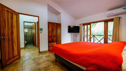 a bedroom with a red bed and a large window at Casa tropical - Fabulous tropical house in Tamarindo