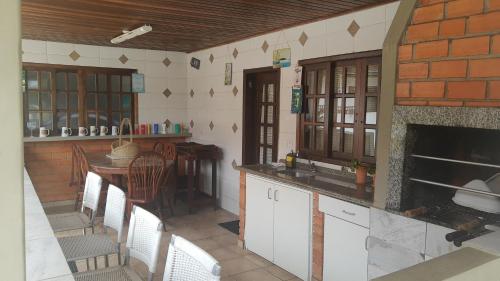 uma cozinha com lareira, mesa e cadeiras em Recanto da Família em Guaratuba
