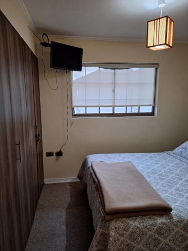 1 dormitorio con 1 cama, TV y ventana en Hospedaje casa Terracota, en La Serena