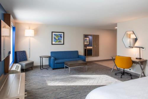 a hotel room with a bed and a blue couch at Holiday Inn Express & Suites Sioux City-South by IHG in Sioux City