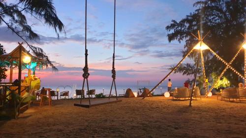 a group of swings on a beach at sunset at Estella Phuket Mai Khao Beach Resort in Mai Khao Beach
