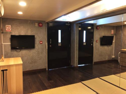 a hallway with two black doors and a flat screen tv at Espace Elastique B&B with contactless check-in in Hong Kong