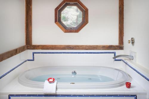 a bathroom with a bath tub with a clock on the wall at West Hill House B&B in Mad River Valley in Warren