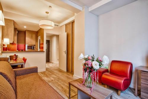 un salon avec un canapé et une table avec des fleurs dans l'établissement Le City - Parking and comfort in the city centre, à Caen