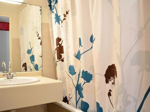 La salle de bains est pourvue d'un rideau de douche avec des fleurs bleues. dans l'établissement Appartement 2 pièces, terrasse, parking privé, proche plage, 6 couchages - Le Lavandou - FR-1-251-547, au Lavandou
