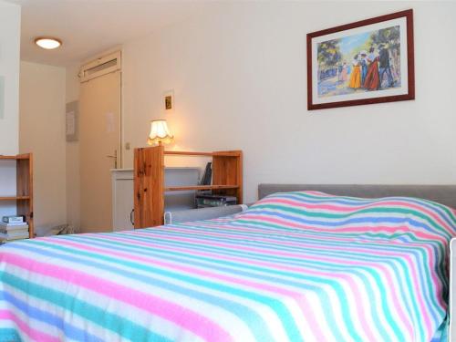 - une chambre avec un lit et une couverture rayée colorée dans l'établissement 2 Pces, 4 Couchages, Terrasse, Parking, Piscine, Proche Plage et Commerces - Le Lavandou - FR-1-251-558, au Lavandou