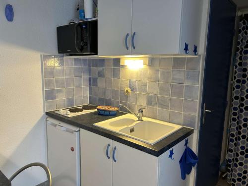 une petite cuisine avec un évier et une cuisinière dans l'établissement Deux Pièces avec Terrasse, Cour Privée et Piscine - Le Grau-du-Roi - FR-1-250-264, au Grau-du-Roi