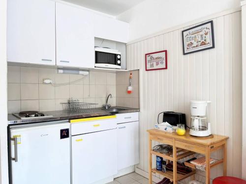 une cuisine avec des armoires blanches et un comptoir dans l'établissement Appartement T2 Cabine, 6 Couchages, Terrasse Ouest, 100m Plage et Commerces, Parking Privatif - FR-1-251-530, au Lavandou