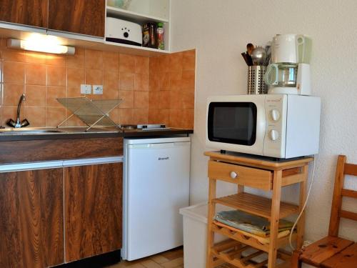 La cuisine est équipée d'un réfrigérateur blanc et d'un four micro-ondes. dans l'établissement Studio 4 couchages proche plage avec parking et balcon au Lavandou - FR-1-251-557, au Lavandou