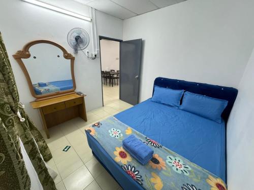 sypialnia z niebieskim łóżkiem i lustrem w obiekcie Homestay Cikgu Iqa (Muslim) w mieście Kuala Kangsar