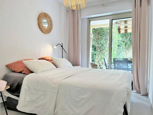 um quarto com uma grande cama branca e uma janela em Appartement Bormes-les-Mimosas, 3 pièces, 5 personnes - FR-1-251-575 em Bormes-les-Mimosas