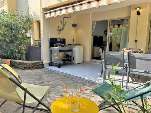 une terrasse avec des chaises et une table avec des verres à vin. dans l'établissement Magnifique 3 pièces RDJ à 250m de la plage - Clim, Terrasse, Garage, 5 couchages - FR-1-251-575, à Bormes-les-Mimosas